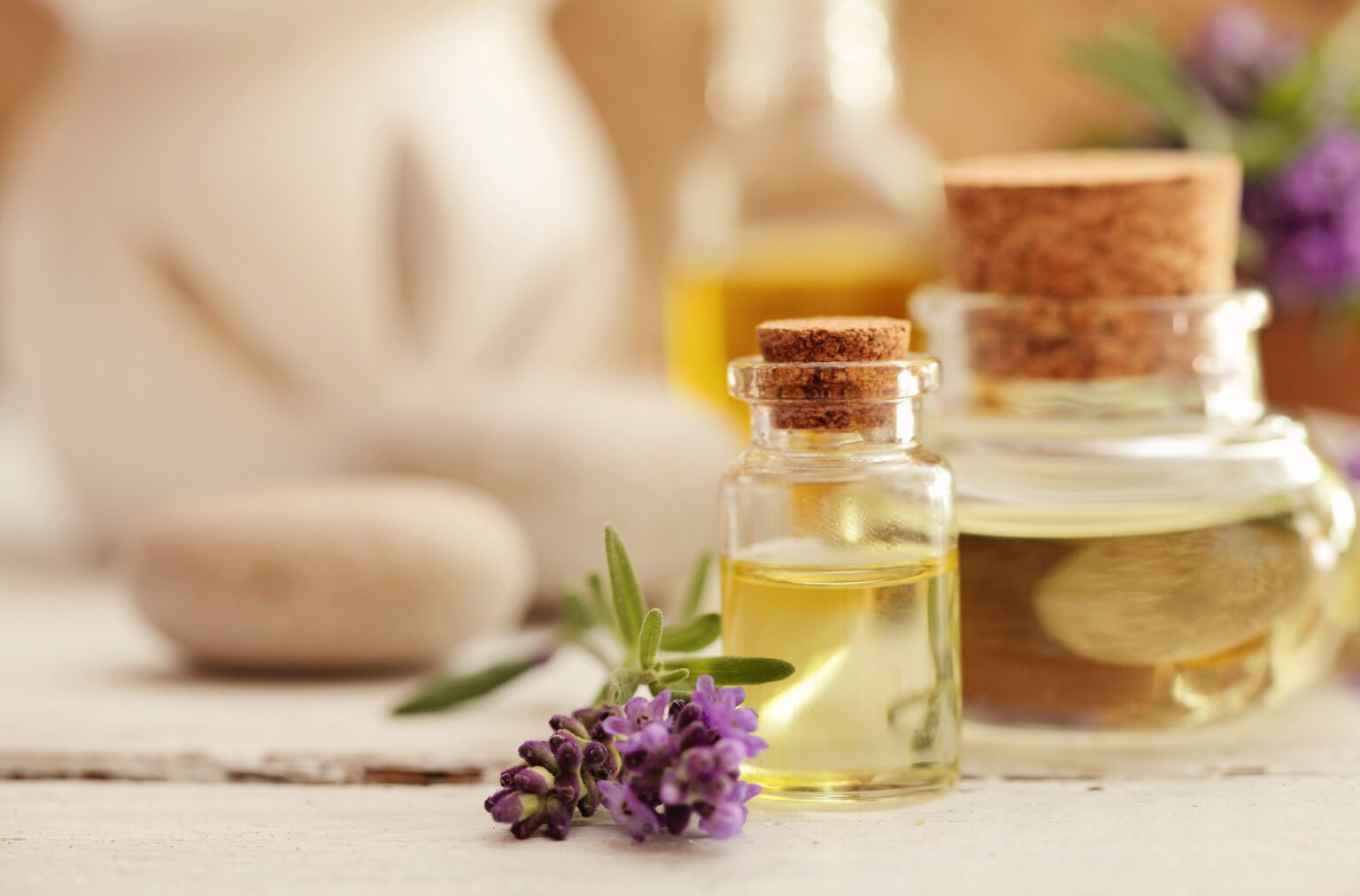 Glass bottles of aromatherapy oil beside a sprig of lavender