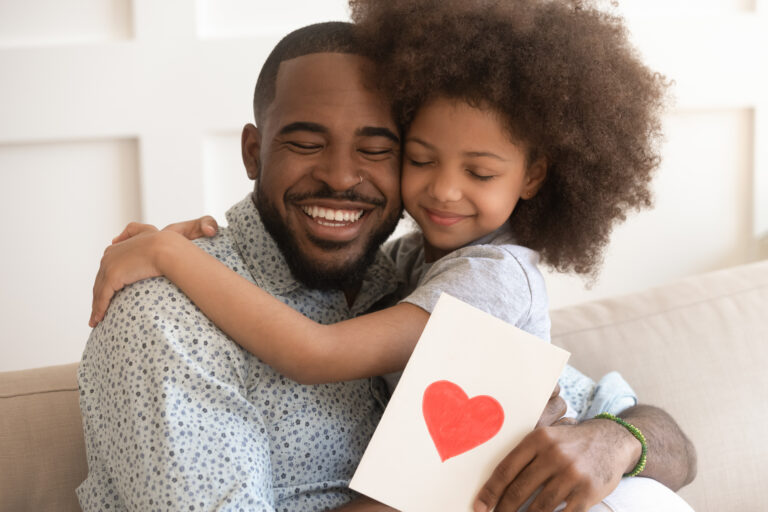 African dad embracing daughter holding greeting card on fathers day