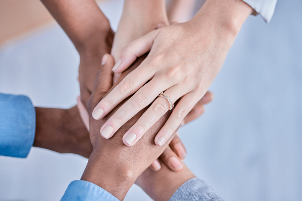 Stack of hands from a group of people placed together in a show of community