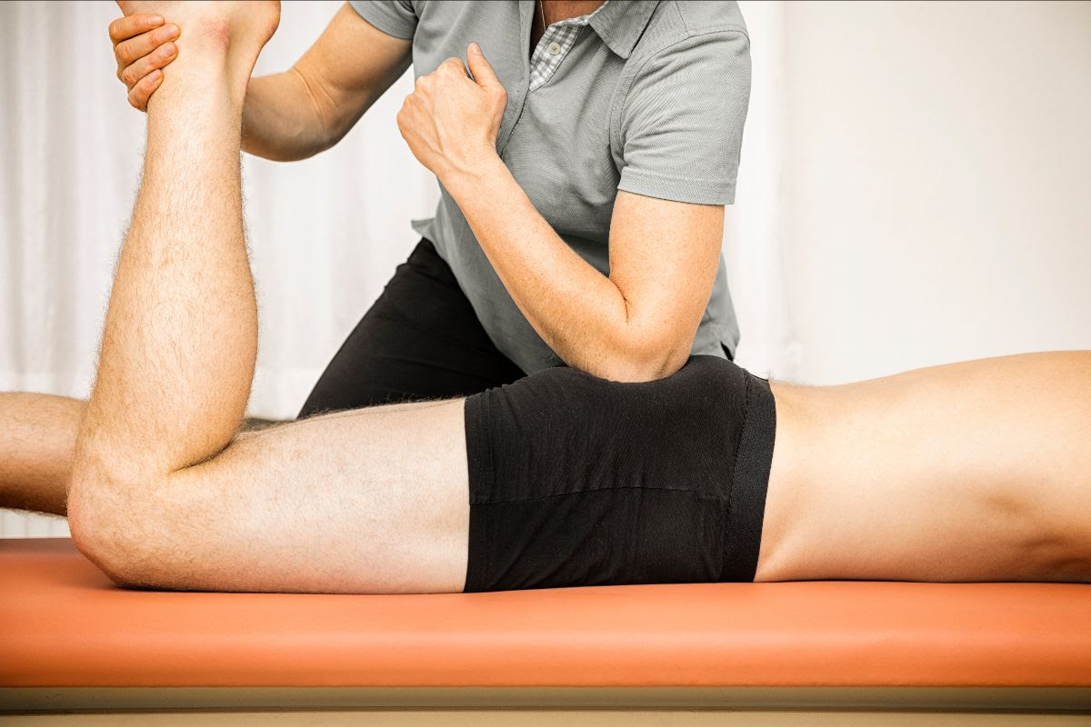 Massage therapist stretching a client's leg during a sports massage